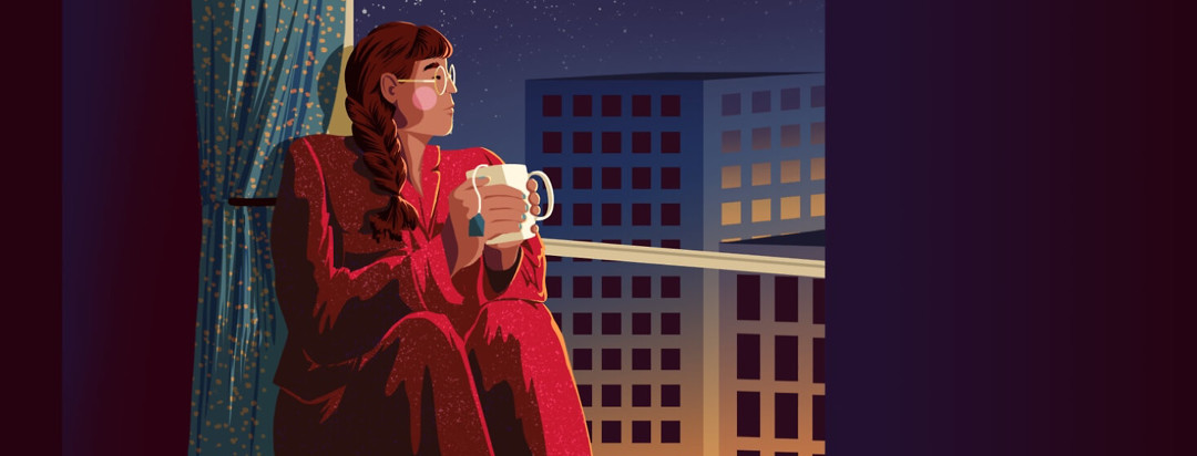 A woman in pajamas sits in a big window holding a cup of tea
