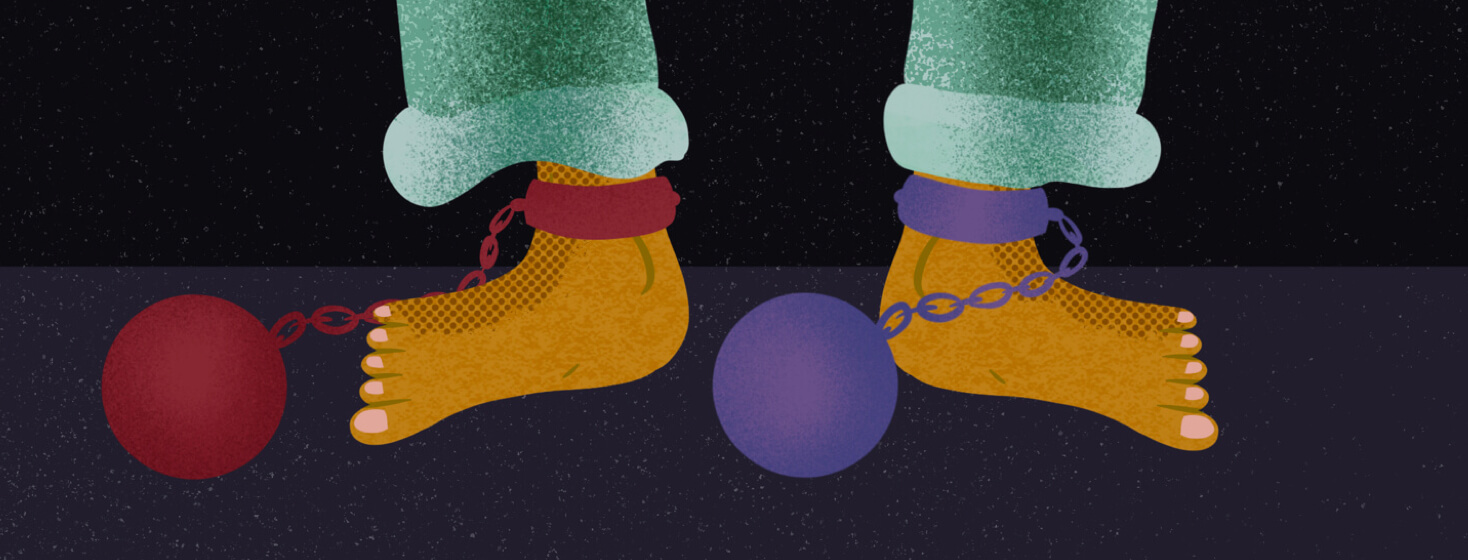 Two feet with a different ball and chain on each ankle