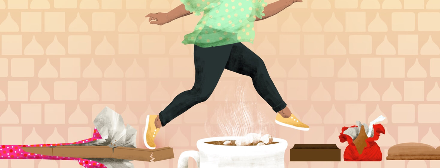 A woman lightly jumps from a cracking bar of milk chocolate over a mug of hot cocoa, onto a square of dark chocolate